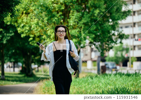 一位年輕女子帶著智慧型手機在城市中奔跑 115931546