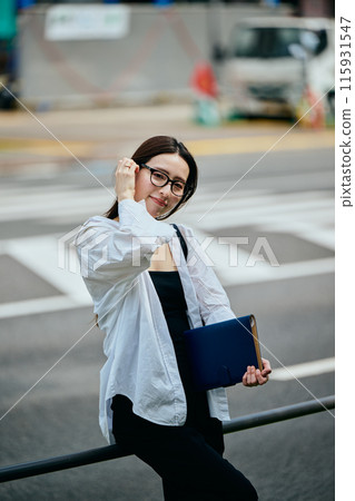 一個帶著筆記本走路的年輕女子 一個帶著筆記本走路的年輕女子 115931547