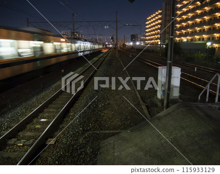 Railroad tracks and train light trails at night 115933129