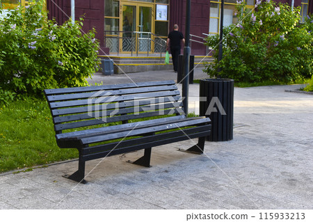 A black wooden bench in the city in the evening. A place to relax in the park. A black wooden bench in the city in the evening. A place to relax in the park. 115933213