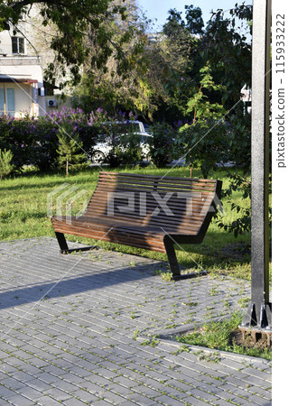 A black wooden bench in the city in the evening. A place to relax in the park. A black wooden bench in the city in the evening. A place to relax in the park. 115933222