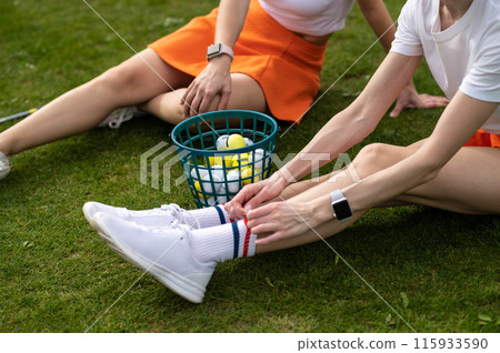 Unrecognizable women golfers sitting by the golf cart on the green lawn 115933590