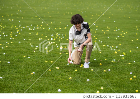 Dark-haired young guy training in a golf club 115933665
