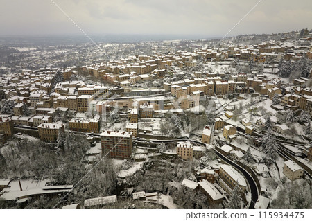 Aerial winter landscape of dense historic center of Thiers town in Puy-de-Dome department, Auvergne-Rhone-Alpes region in France. Rooftops of old buildings and narrow streets at snowfall 115934475