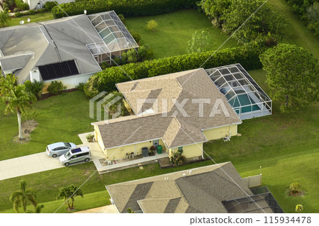 Aerial view of typical contemporary american private house with roof top covered with asphalt shingles and green lawn on yard 115934478