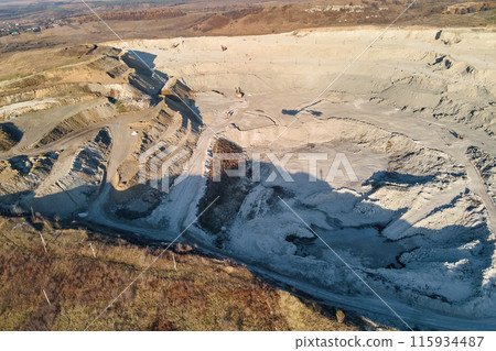 Aerial view of open pit mine of sandstone materials for construction industry with excavators and dump trucks. Heavy equipment in mining and production of useful minerals concept Aerial view of open pit mine of sandstone materials for construction industry with excavators and dump trucks. Heavy equipment in mining and production of useful minerals concept 115934487