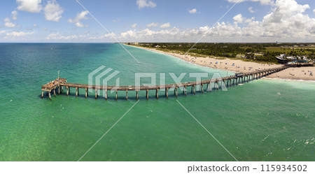 Summer landscape at Venice fishing pier in Florida. Ocean surf waves crashing on warm sandy beach Summer landscape at Venice fishing pier in Florida. Ocean surf waves crashing on warm sandy beach 115934502