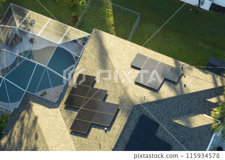 Aerial view of typical american building roof with rows of blue solar photovoltaic panels for producing clean ecological electric energy. Renewable electricity with zero emission concept Aerial view of typical american building roof with rows of blue solar photovoltaic panels for producing clean ecological electric energy. Renewable electricity with zero emission concept 115934578