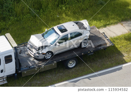 Tow truck loading crashed car on accident site. Emergency services personnel and vehicles responding to vehicle crash on American street. First responders helping on road in the USA Tow truck loading crashed car on accident site. Emergency services personnel and vehicles responding to vehicle crash on American street. First responders helping on road in the USA 115934582