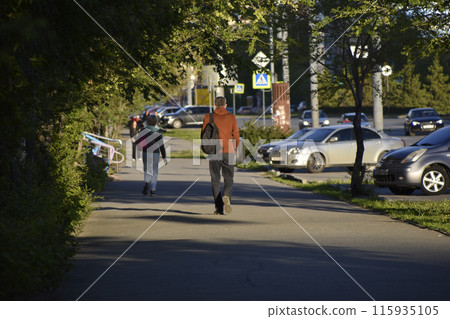 A sunny summer street and people leaving. People walking down the street. 115935105