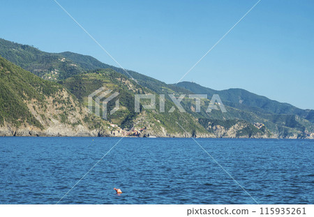 Coastline view from distance of the area Cinque Terre coast with Vernazza and Corniglia Villages of National Park with ligurian sea and blue sky. La Spezia, Liguria, Beautiful mountain. Copy space Coastline view from distance of the area Cinque Terre coast with Vernazza and Corniglia Villages of National Park with ligurian sea and blue sky. La Spezia, Liguria, Beautiful mountain. Copy space 115935261