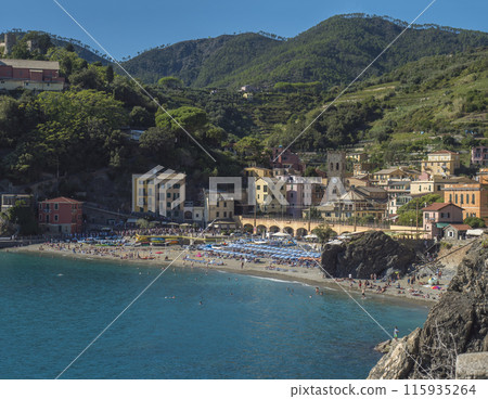 Picturesque view of Monterosso al Mare with beach, colorful houses, train rails, bell tower and Torre Bastioni with green cliffs, clear blue sky and sea. National park Cinque Terre, Liguria, Italy 115935264