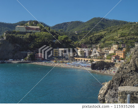 Picturesque view of Monterosso al Mare with beach, colorful houses, train rails, bell tower and Torre Bastioni with green cliffs, clear blue sky and sea. National park Cinque Terre, Liguria, Italy 115935266