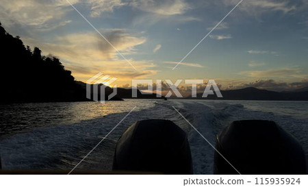 Sunset boat ride around an island with mountains in the background 115935924