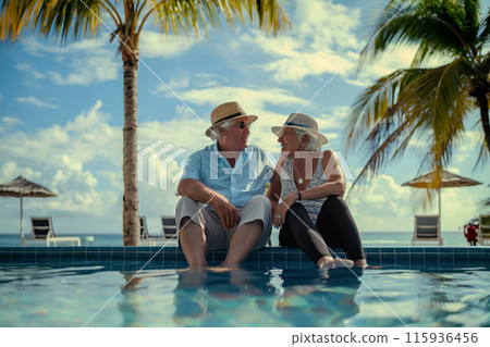 Relaxing by the pool at a resort, an elderly couple sits by the pool and dips their feet in the water, the tropical ambiance creates the perfect backdrop for a relaxing vacation. 115936456