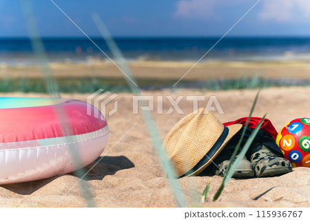 Beach toys and accessories on a sandy shore Beach toys and accessories on a sandy shore 115936767