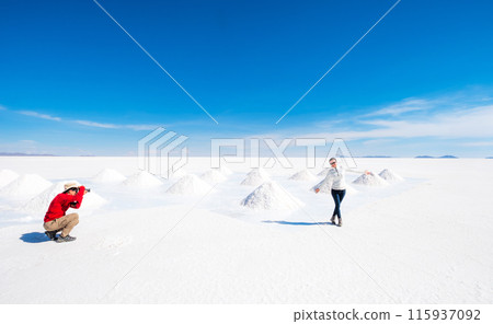 Tourists taking photos at sault banks on background of sunshine Salar de Uyuni Tourists taking photos at sault banks on background of sunshine Salar de Uyuni 115937092