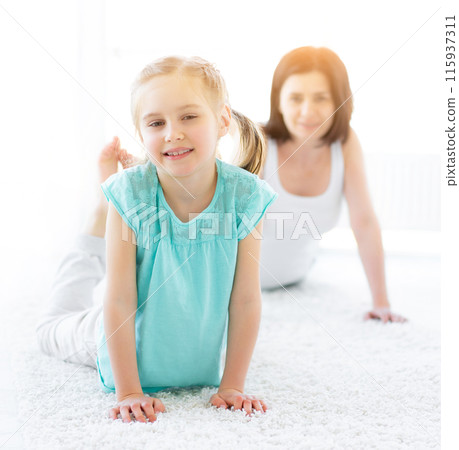 Pretty little girl doing physical exercises with mother at home Pretty little girl doing physical exercises with mother at home 115937311