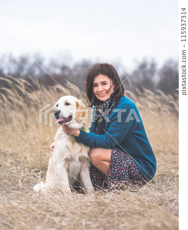 Happy woman next to cute young dog outside in early spring Happy woman next to cute young dog outside in early spring 115937314