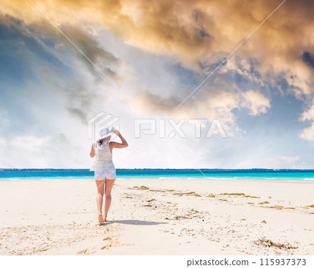 beautiful smiling girl in hat on a beach of blue ocean and sky on the background at sunset beautiful smiling girl in hat on a beach of blue ocean and sky on the background at sunset 115937373