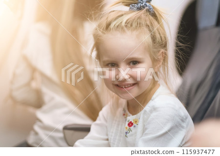 Young blonde girl smiling and looks at camera on tha aircraft board. 115937477