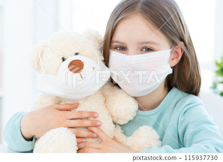 Little girl with plush teddy wearing medical masks at home Little girl with plush teddy wearing medical masks at home 115937730