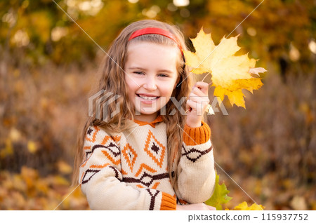 Smiling little girl with autumn leaves in park 115937752