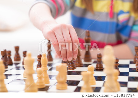 Little kid moving black chess figure, close-up with soft focus Little kid moving black chess figure, close-up with soft focus 115937784