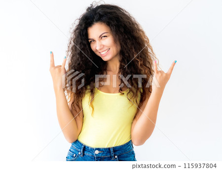 Attractive young girl showing devil horns gesture Attractive young girl showing devil horns gesture 115937804
