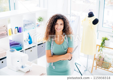 Smiling girl tailor with scissors in a sewing atelier 115938318