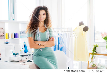Pretty tailor standing in sewing atelier with measuring tape 115938325