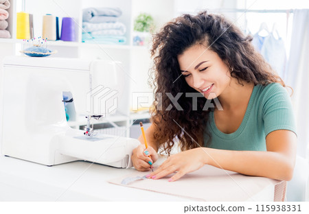 Happy tailor measuring cloth in light workroom 115938331