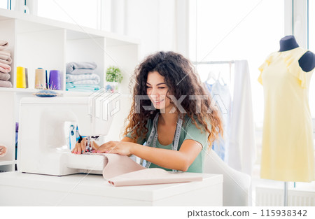 Happy seamstress sewing new design in workshop Happy seamstress sewing new design in workshop 115938342