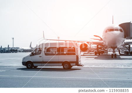 White VIP service van running on airport taxiway with big passenger airplane on background. Business class service at airport. Security intelligence agency hurrying at airfield 115938835