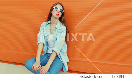 Portrait of modern stylish young woman in white glasses, casual clothing posing on orange background 115939451