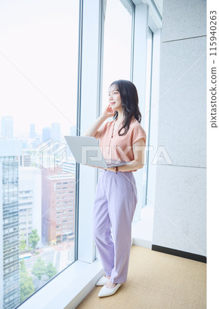 Woman looking at a computer by the window in an office 115940263