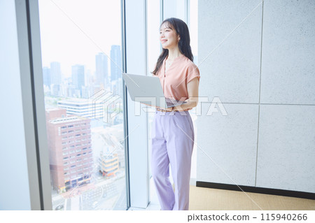 Woman looking at a computer by the window in an office 115940266