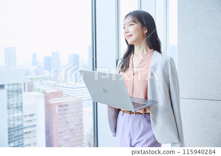一位女士在辦公室窗邊看著電腦 115940284