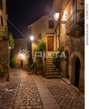 Cobblestone alley bathed in warm lights at dusk 115941373