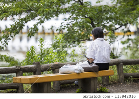 一位孤獨的中年婦女獨自坐在公園長椅上的照片 一位孤獨的中年婦女獨自坐在公園長椅上的照片 115942016