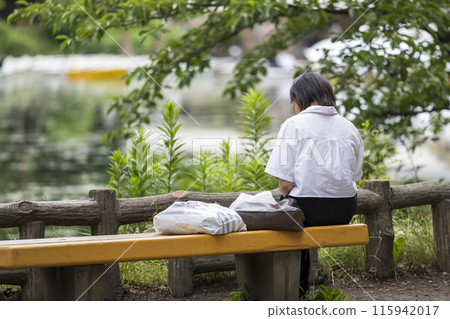 一位孤獨的中年婦女獨自坐在公園長椅上的照片 115942017
