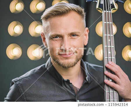 Close-up of smiling musician holding guitar with stage lights 115942314
