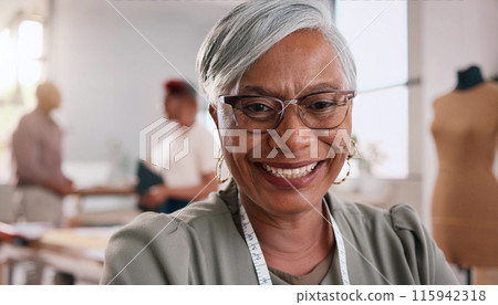 Cheerful mature woman with glasses and measuring tape smiles warmly in a bright workspace 115942318