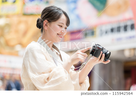 A girl with a camera taking pictures with her hobby single-lens reflex camera while sightseeing in the downtown area of the city | Photographer image A girl with a camera taking pictures with her hobby single-lens reflex camera while sightseeing in the downtown area of the city | Photographer image 115942564