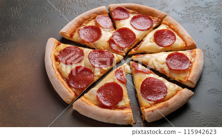 A pepperoni pizza sliced into 8 pieces on a dark surface 115942623
