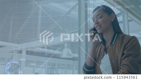 Image of graphs, circles and trading board, biracial businesswoman talking on phone in corridor 115943561