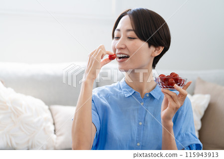 Young woman eating cherry tomatoes lifestyle image 115943913