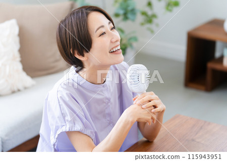 使用手扇的年輕女子 — 生活方式形象 使用手扇的年輕女子 — 生活方式形象 115943951