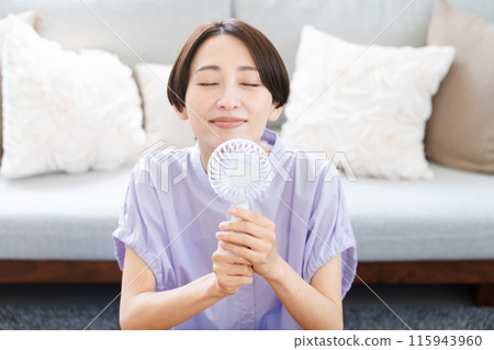 Young woman using a hand fan Lifestyle image 115943960