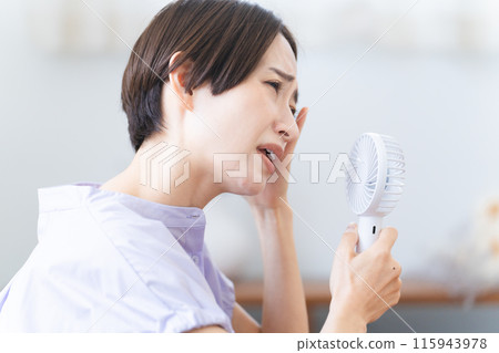 Young woman using a hand fan Lifestyle image Young woman using a hand fan Lifestyle image 115943978
